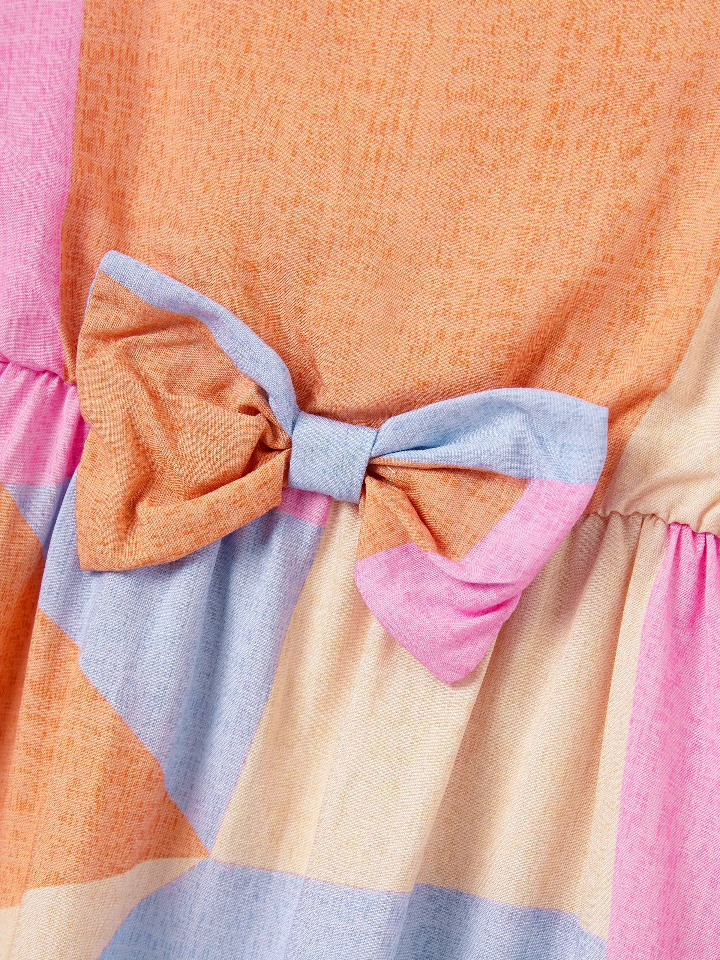 Colorful dress with a large bow detail on a multicolored background