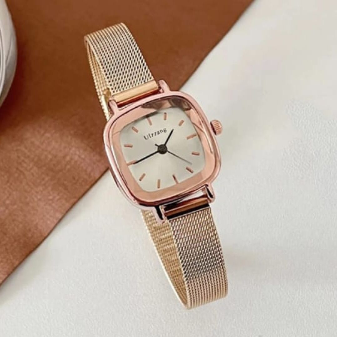 Rose gold watch with a white face on a light brown surface